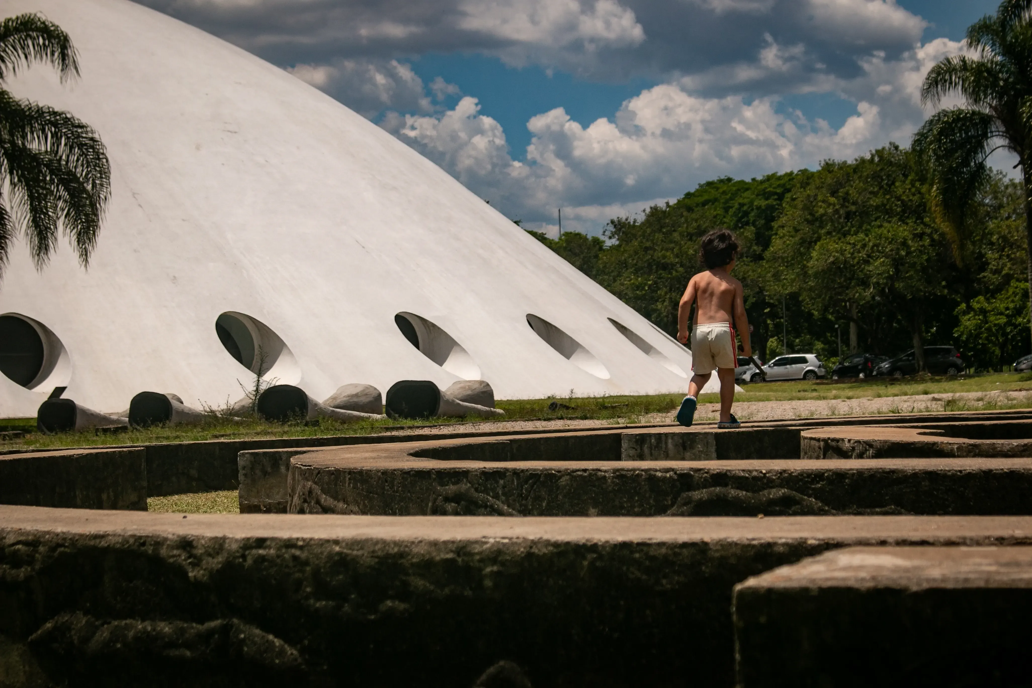 Child walking near Ibirapuera Auditorium on a sunny day