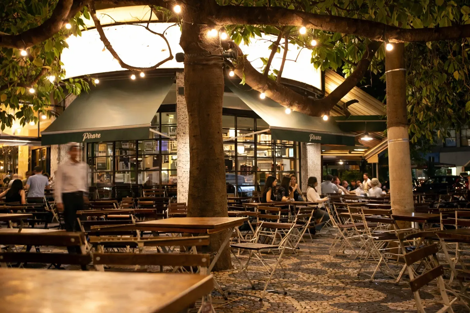 Outdoor restaurant patio at night with string lights and people dining