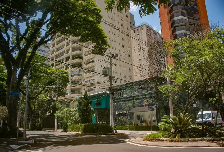 Tree-lined intersection with a mural wall and tall apartment buildings