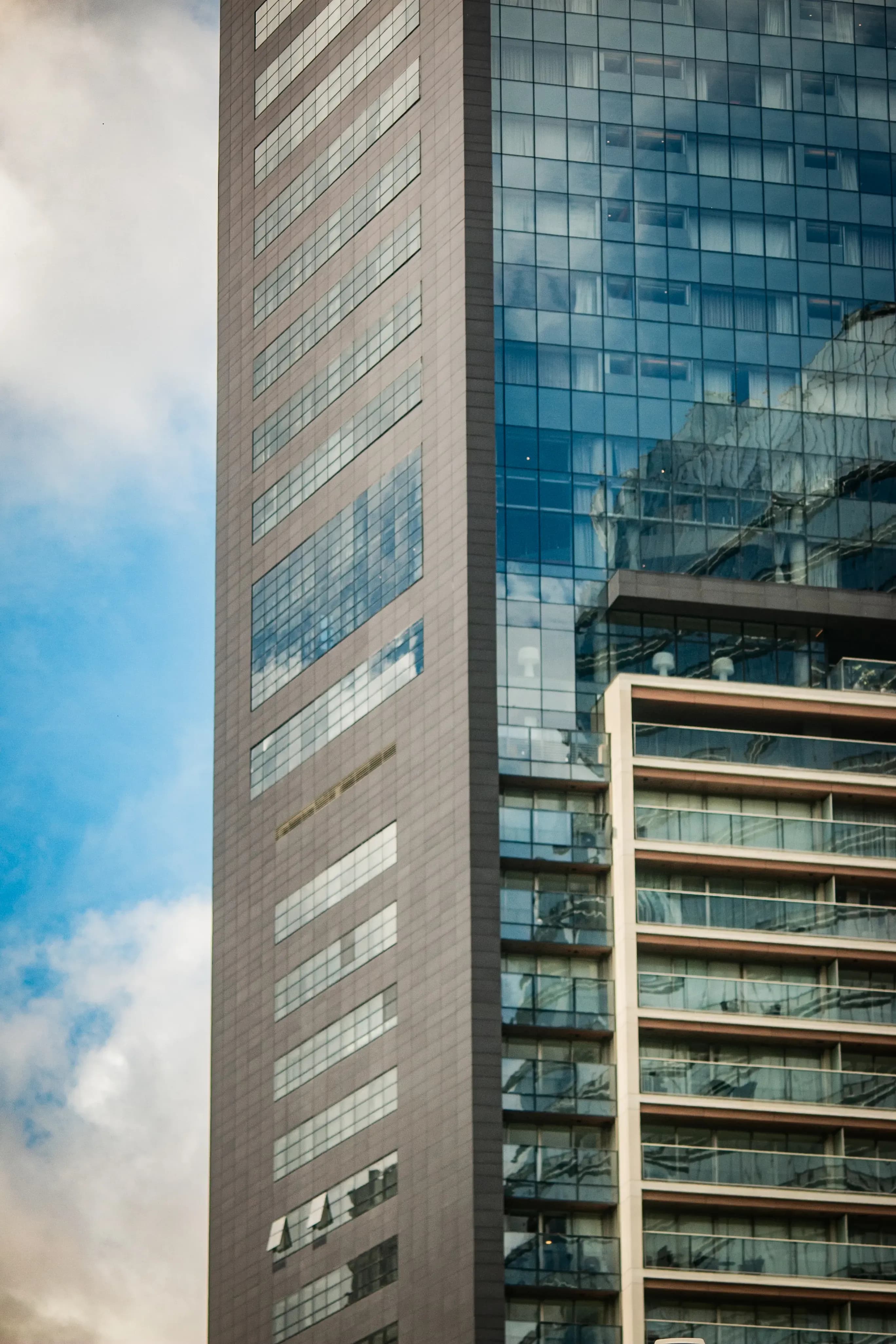 Close-up of a tall modern tower facade with blue glass and concrete panels