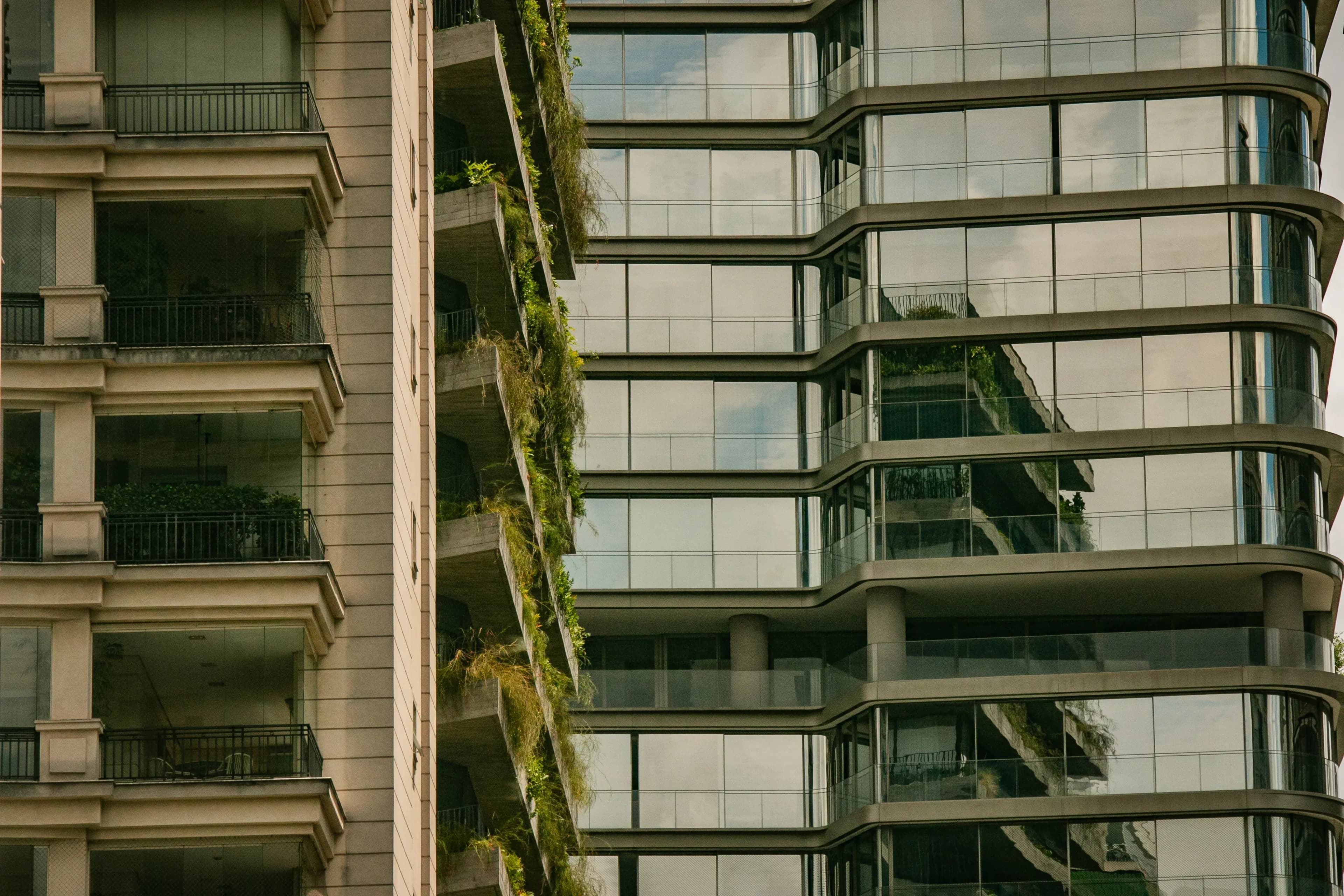 Close-up of modern apartment buildings with glass facade and planted balconies