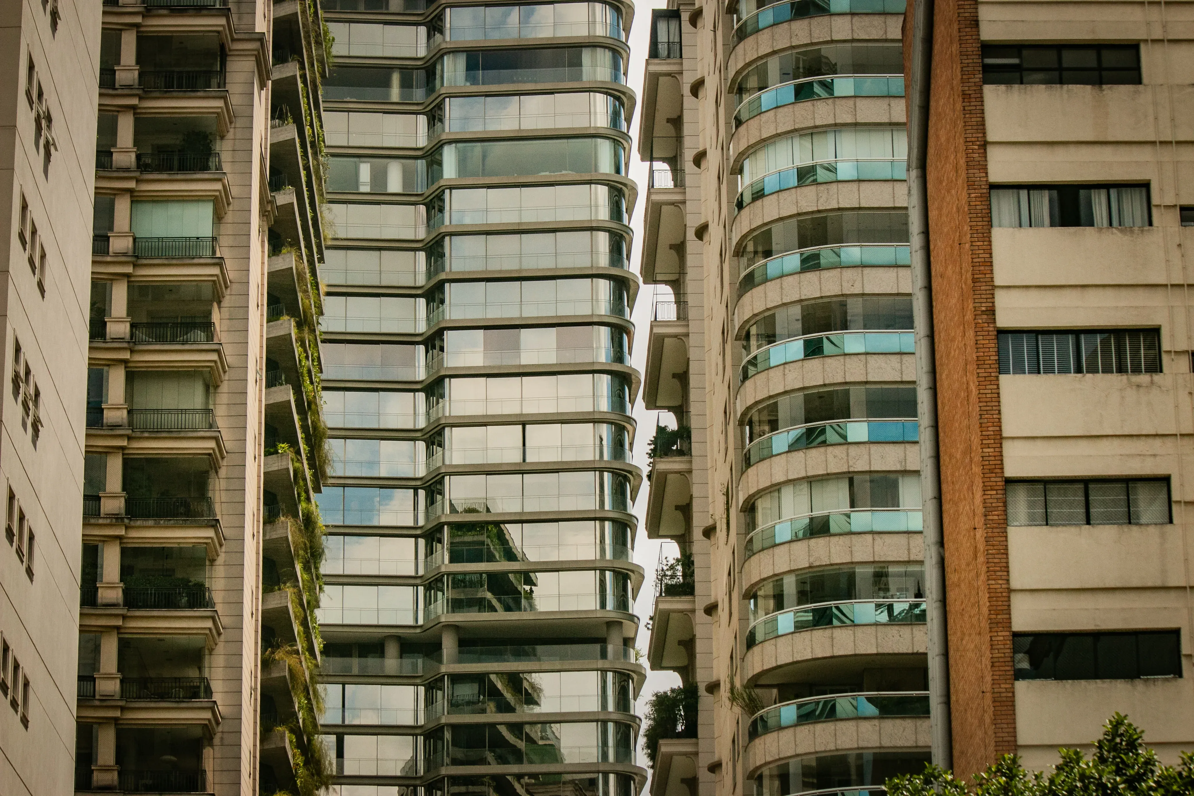Narrow street view framed by tall residential buildings with curved glass balconies
