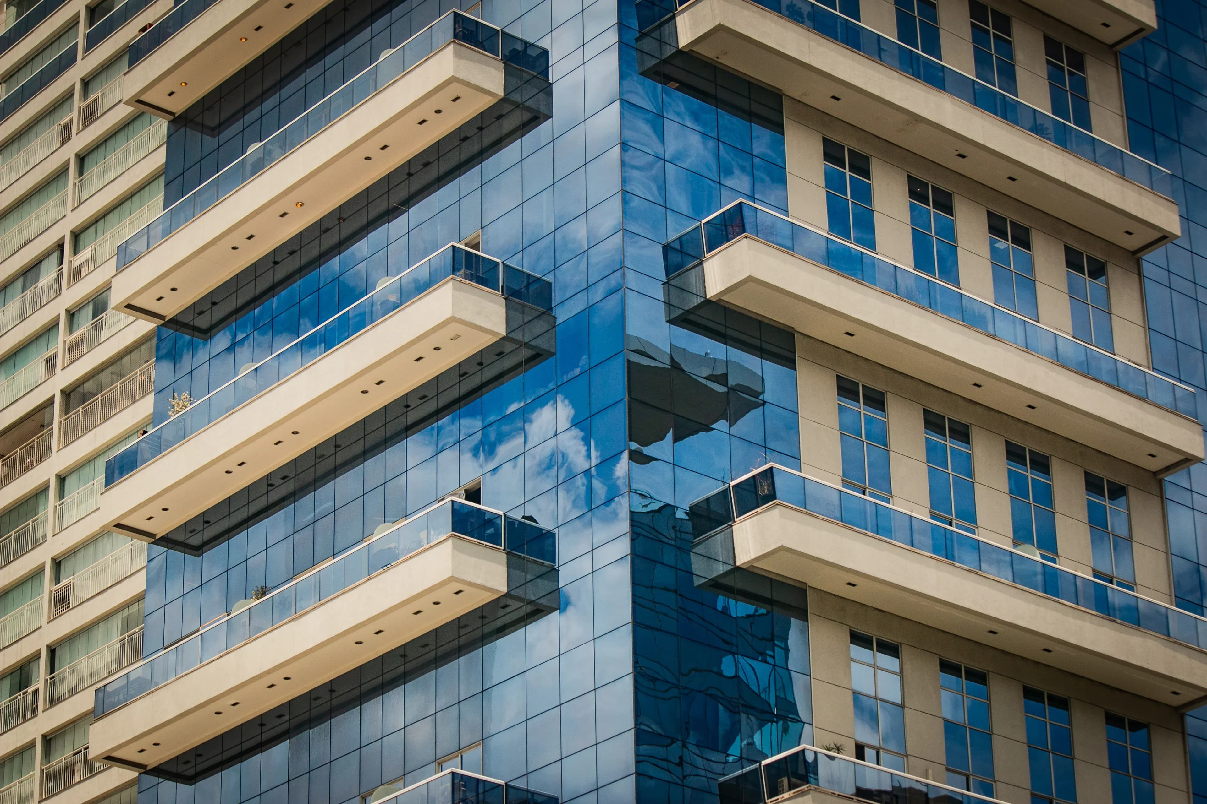 Close-up of a blue-glass tower with stacked balconies