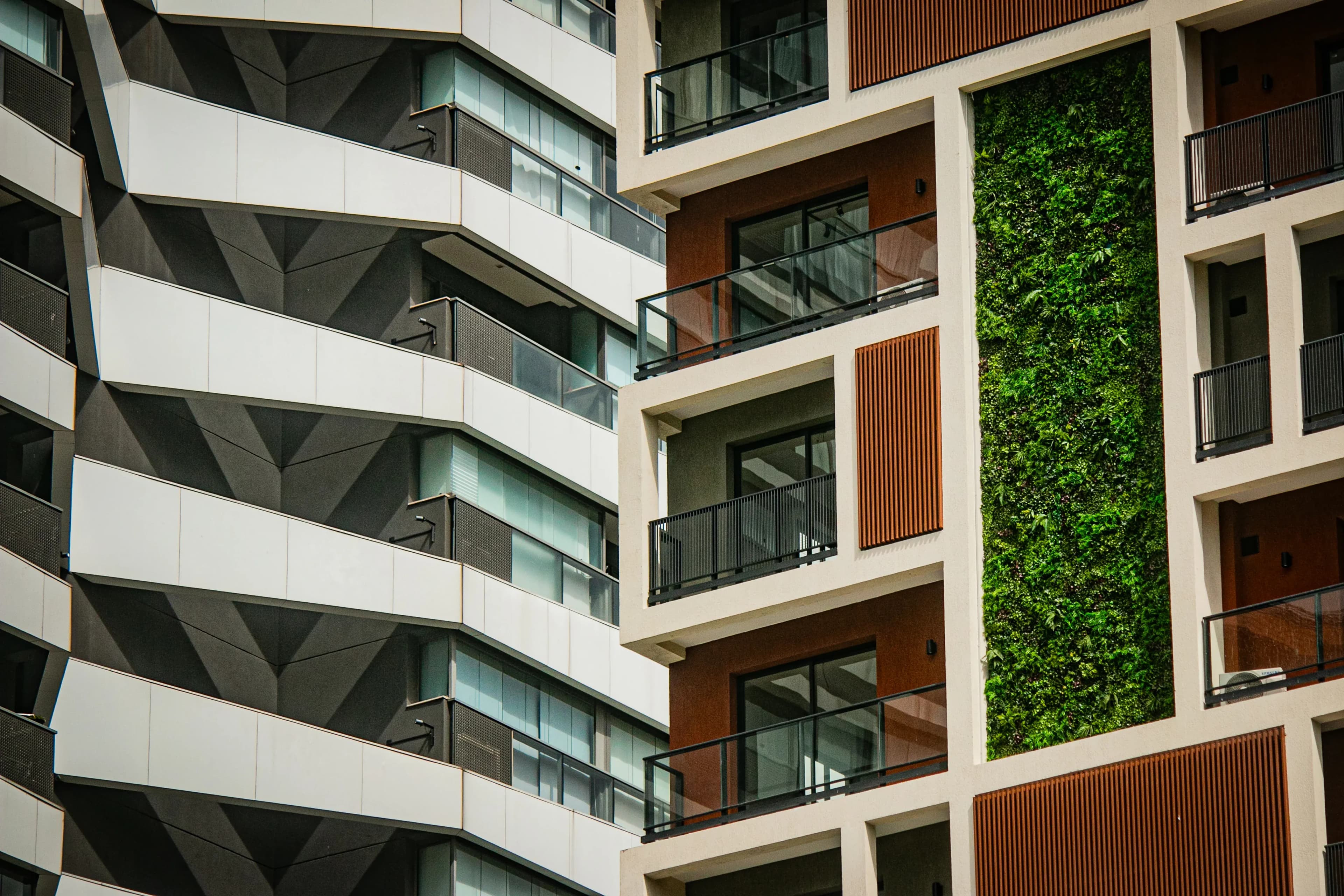 Modern apartment buildings with balconies and a vertical green wall